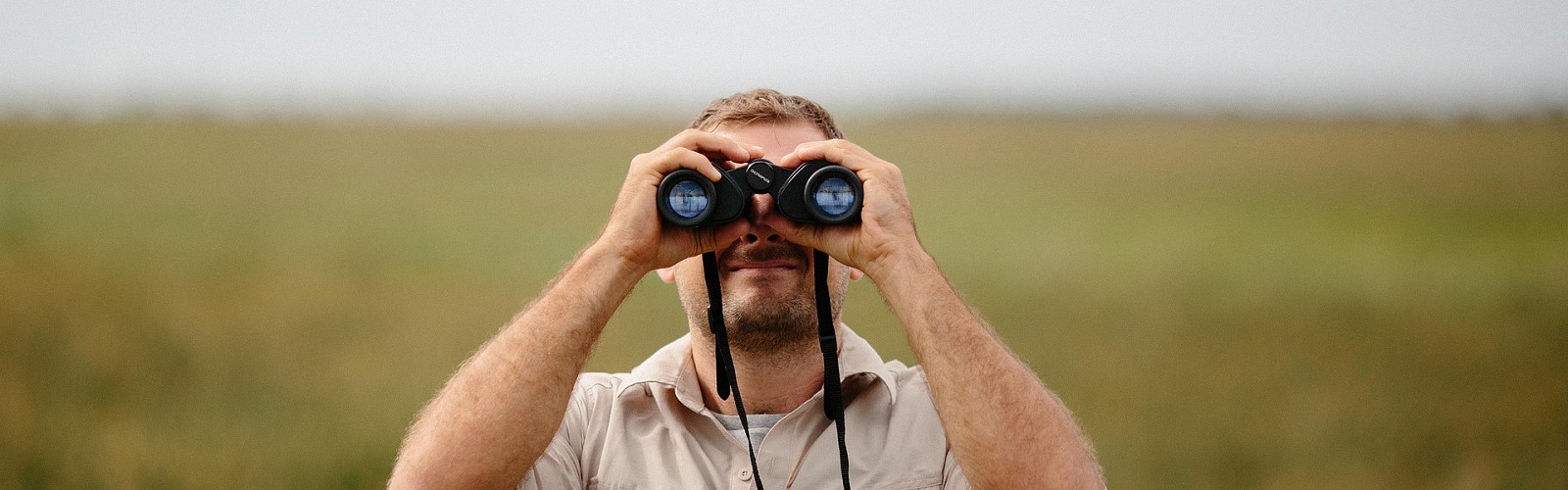 man looking through binoculars (StockSnap / pixabay)